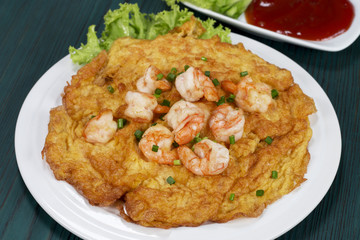 Omelet with shrimp on a wooden table green, thai food