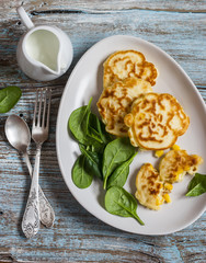 Corn fritters and fresh spinach on a wooden background. Vegetarian Breakfast or snack, top view