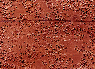 Grungy red rubber surface with bubbles and scratches.