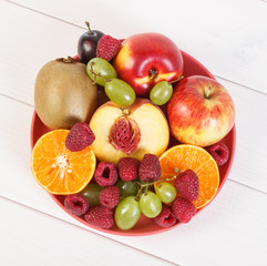 Fresh ripe fruits on plate lying on white boards