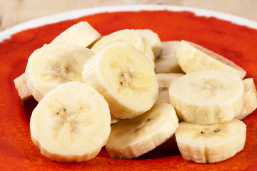 Slices of fruit of banana on red plate , close up