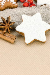 Fototapeta na wymiar gingerbreads in star shape, red berries and nuts on brown wrapping paper background 