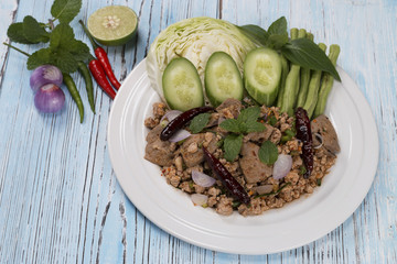 spicy minced pork salad on the wooden table in blue, thai food