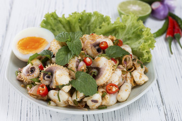 spicy squid salad on the wooden table in white,thai food