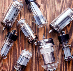 closeup picture with different tipes of electronic vacuum tubes on wooden background.