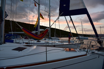 Three yachts anchoring in bay with person lying in hammock