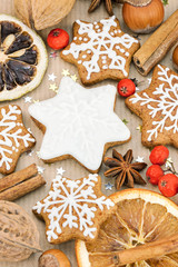 christmas homemade star shaped gingerbread cookies, nuts, spices, red berries brown on wrapping paper background