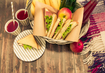 A picnic with lemonade,picnic basket, sandwiches, bananas, apples, plaid
