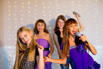 Group of happy girls singing on karaoke
