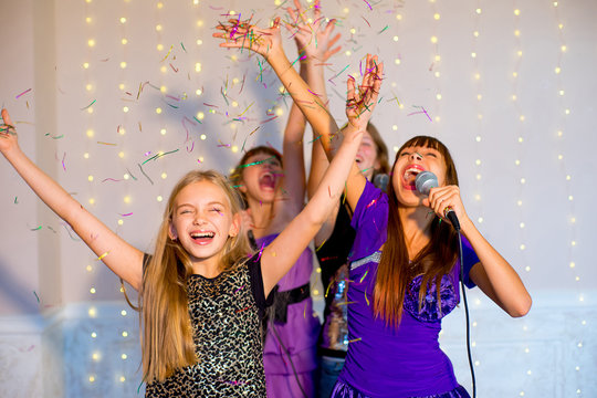 Group of happy girls singing on karaoke