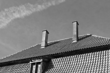 Old tiled roof with chimneys and window in black and white