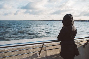 Woman looking at the sea at winter from pier.