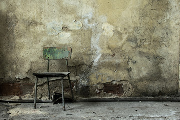 view of a wall of an old abandoned factory building,old wooden chair on moldy wall