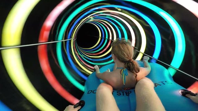 Slope down by water slide in water park. Fun travel inside of the multi color tube at aqua park filmed on action camera. Slow motion.