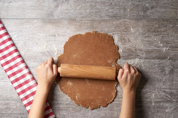 Hands rolling out Cookie dough on table from above