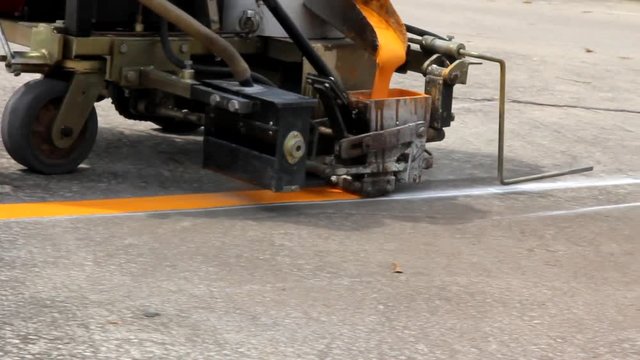 Man painting the yellow line on the concrete floor at car park