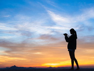 Silhouette of woman shooting with camera at sunset,mountain