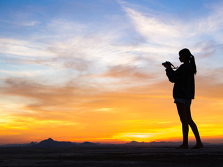 Girl photographer with camera at sunset