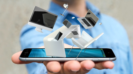 Businessman holding flying desk laptop phone and tablet in his h