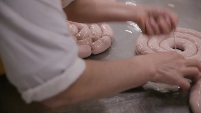 Sausages production. Butcher making meat delicacy on a automated meat processing equipment. HD.