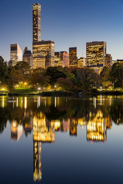 The Lake in Central Park at twilight with New York City lights and Manhattan Midtown skyscrapers reflecting into the lake