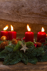 Evergreen fir tree advent garland with four red burning candles on wooden bakcground with copy space