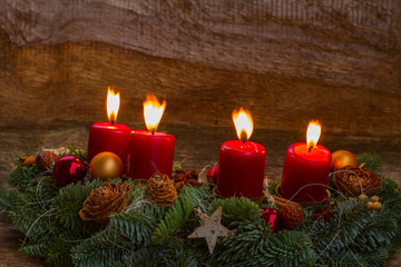 Evergreen fir tree advent garland with four red burning candles on wooden bakcground