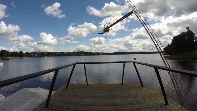 Bridge and wakeboarding equipment  by resort lake on sunny cloudy windy summer day, time lapse 4K
