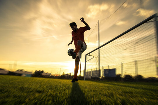 Silhouette of a soccer player on a football field at sunset. - Powered by Adobe