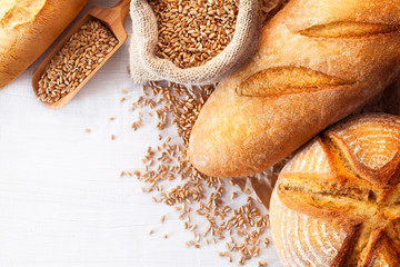 Assortment of baked bread on white wooden table background