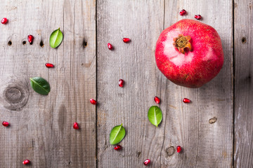 Whole red ripe juicy pomegranates on rustic wooden unpainted table