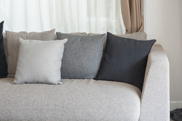 set of pillows on modern sofa with white curtain