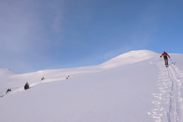 backcountry skier climbing a mountain in the Swiss Alps for an off-piste descent