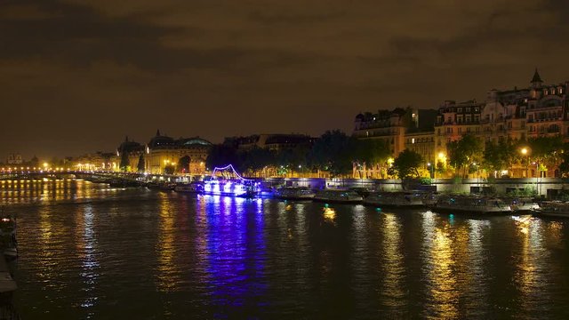 River Seine in Paris, France at night with beautiful reflections in the water. Traffic lightstreaks in the background.