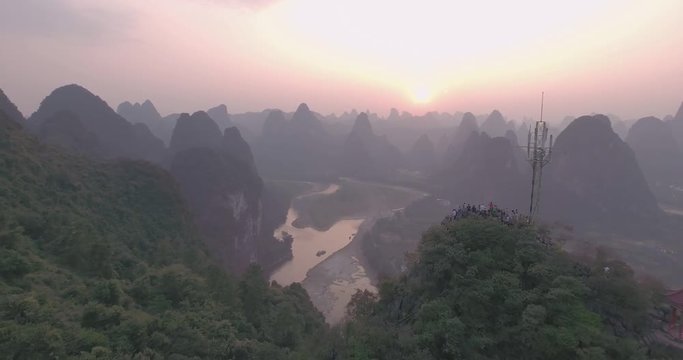 Breathtaking aerial establishing shot over beautiful limestone karst mountain scenery,Li River covered with haze at sunset in Xingping fishing village,Yangshuo County,China.Mountain landscape top view