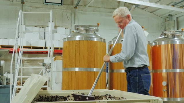 Sequence 2 video: Winemaker working in the winery. Stirred raw materials for wine. Punch down the cap