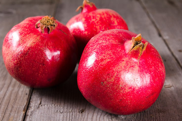 Some whole red pomegranate on rustic wooden unpainted table