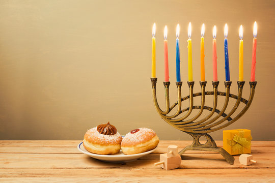 Jewish holiday Hanukkah celebration with menorah and sufganiyot on wooden table