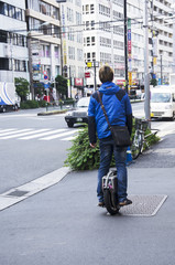 Japanese people standing and riding unicycle  on pathway beside