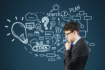 Side view of businessman thinking near blue wall with sketches