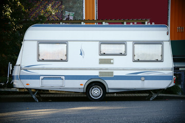 Campinganhänger / Ein weißer moderner Wohn- und Campinganhänger aus Blech steht auf einem Parkplatz.
