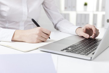 Side view of girl in white shirt typing and writing