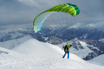 green skier starts with a paraglider in  highlands