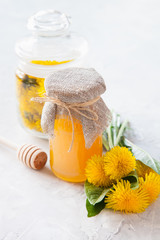 honey and dandelions in a jar on a table, selective focus