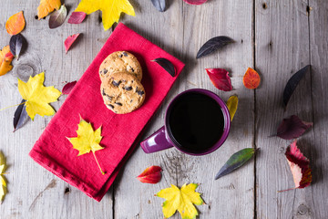 Cup of coffee surounded by red, purple and yellow fall leaves