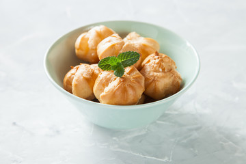 Profiteroles, choux with a cream,  whipped cream, dessert on a plate, selective focus