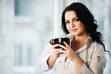 Portrait of young woman holding a cup of coffee.