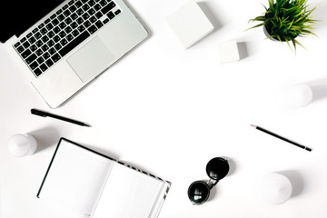 Stylish minimalistic workplace with laptop keyboard, notebook, sunglasses and office plant in flat lay style. White background. Top view.