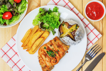 Grilled meat steak serve with tomato sauce, Mashed Potatoes, french fries and vegetable salad, isolated on wooden background, Closed up