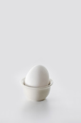 The egg in the stand on a white background. High key, selective focus.